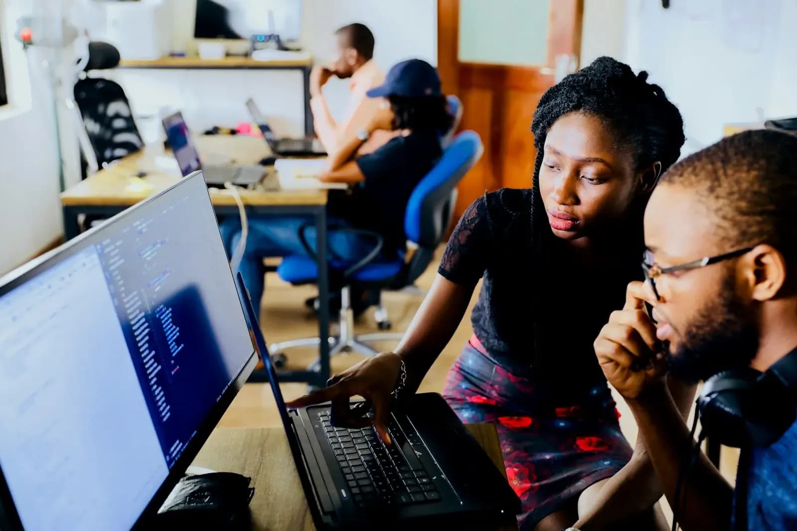 Two colleagues looking at code on a laptop together