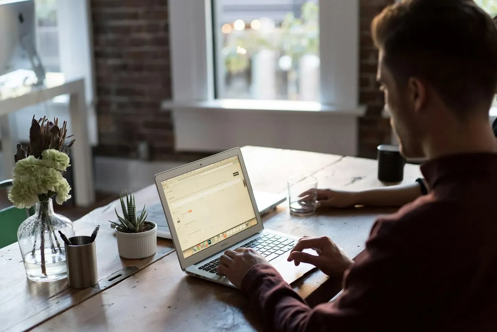 Man working on a laptop at a wooden desk