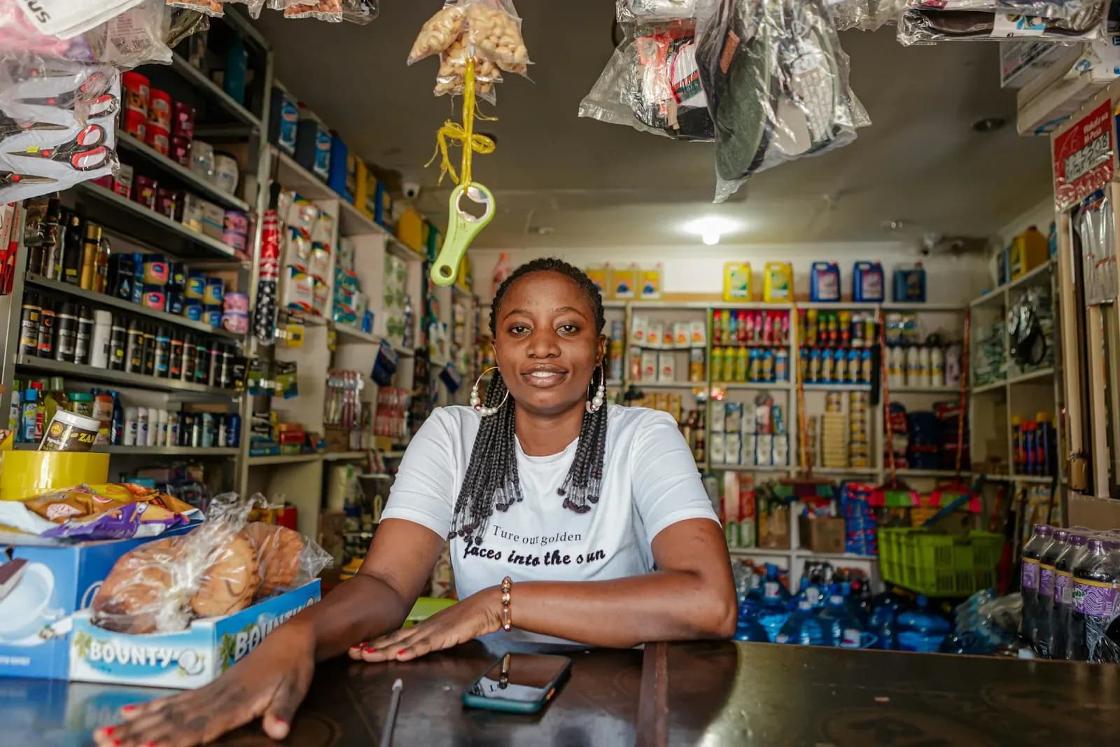 Shop owner smiling behind her counter with a phone in hand