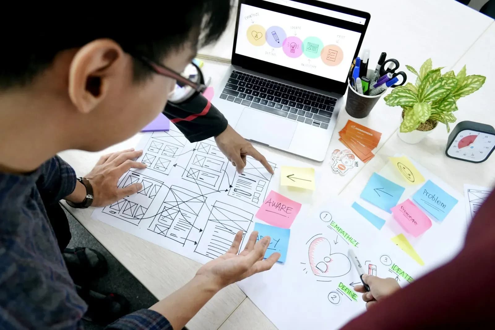Designer sketching website wireframes next to a laptop